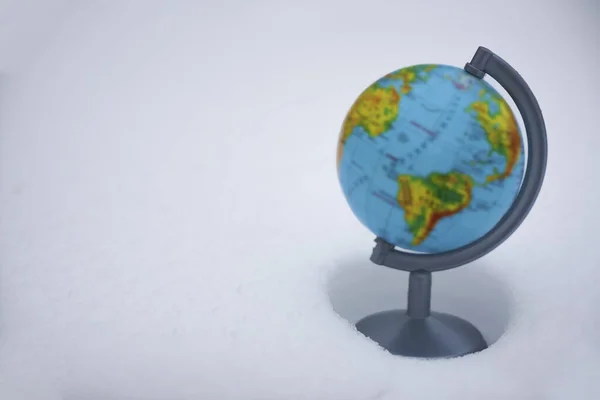 Freezing planet Earth. Large drift of snow. The concept of climate change, ice age, abnormal weather on the planet. globe map on the snow background, selective focus