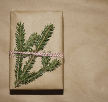 Kahverengi el sanatları kağıdına sarılı hediye kutusu. Kırmızı ve beyaz iplik altında çam dalı. Kırmızı ip. Yazı için boş kopyalama alanı. 