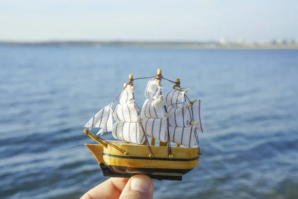 Mannelijke Hand Met Een Boot Zeil Model Blauwe Zee Achtergrond — Stockfoto