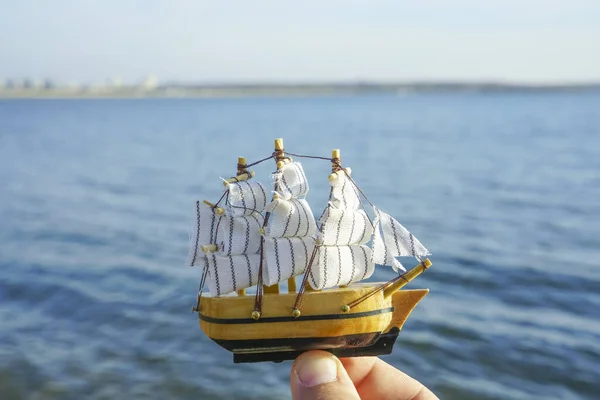 Man Hand Håller Båt Segel Modell Blått Hav Bakgrunden — Stockfoto