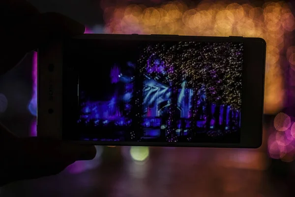 スマホで夜景の写真を撮る男の手 タッチスクリーンに焦点を当てる — ストック写真