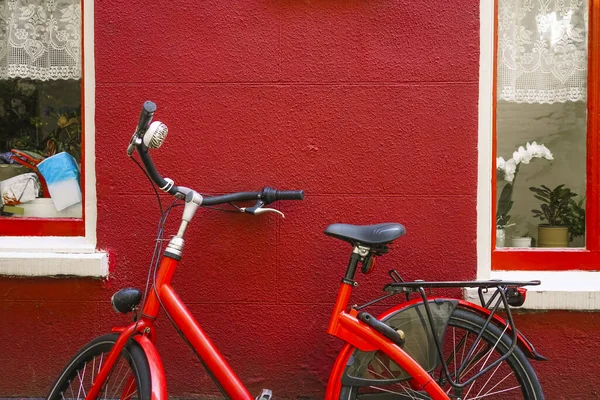 一辆红色自行车停在两扇窗户之间的一座村外 — 图库照片