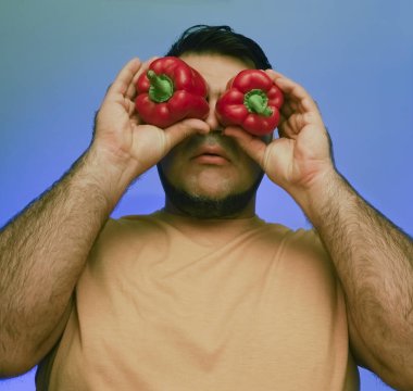 Koca biberleri suratının önünde tutan bir adamın komik resmi. beyaz veya gri arkaplanda izole edilmiş. 