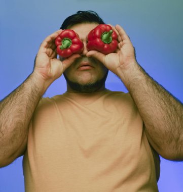 Koca biberleri suratının önünde tutan bir adamın komik resmi. beyaz veya gri arkaplanda izole edilmiş. 