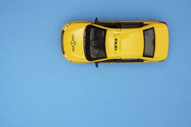Sarı taksi. Plastik ve metal oyuncak modeli mavi kağıttan arka planda izole edilmiş. Yazı için boş kopyalama alanı. en üstteki görünüm. 