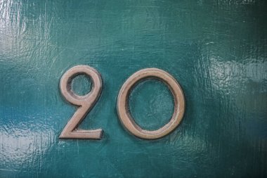 20 numaralı, ince bronz metal kaplı ev. 20 numara yeşil ahşap ön kapıda.