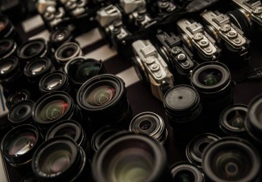 Renkli yansıma önleyici çok katmanlı birçok fotoğraf lensinin yakın çekimi. Masadaki kameralar farklı marka. Objektifle hedefin arkaplanı