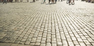 Avrupa 'daki fayanslar ve insanlar yürüyor. Gün batımında kaldırım taşları. Asya Sarayı kilisesine karşı Cobbled Stones 'da güneş ışığı. Güneş ışığı ve güneş ışınları. Tam bina arkası. Birçok turist yürüyor.