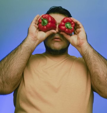 Koca biberleri suratının önünde tutan bir adamın komik resmi. beyaz veya gri arkaplanda izole edilmiş. 