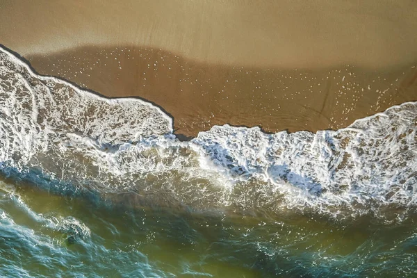 Above vertical view of blue ocean waves and yellow sandy beach - summer holiday vacation concept - travel and scenic place - energy nature outdoors with nobody there