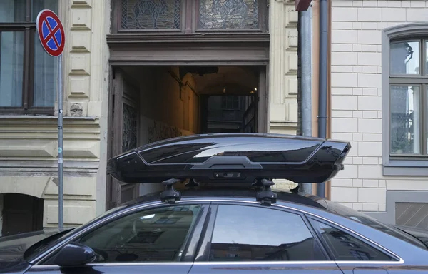 large black box trunk on the roof of a dark modern car. Travel and accessories for transportation. trunk box fixed at roof top of the car