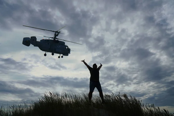 silhouette of man jumping up with hands up. helicopter. combat helicopter flies overhead
