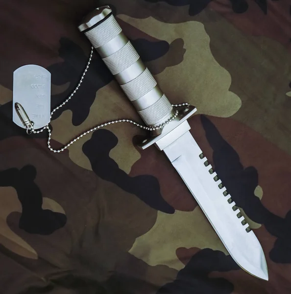 Knife and army token on the background of camouflage. stainless steel. khaki backdrop.