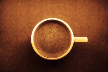 Kahverengi ahşap yüzey arka planında güzel köpüklü beyaz seramik kahve kapağı. 