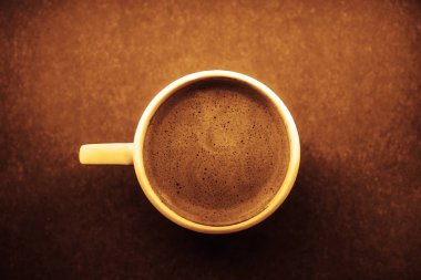 Kahverengi kağıt yüzeyinde güzel köpüklü beyaz seramik americano kahve kapağı.