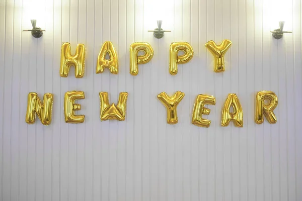 Word - happy new year in english alphabet from yellow (Golden) balloons on a white wall background. holidays and education idea. 2020 happy new year - inscription.