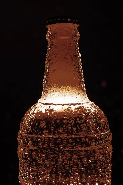 golden Beer with foam - dark beer in transparent  bottle. Isolated on black  background