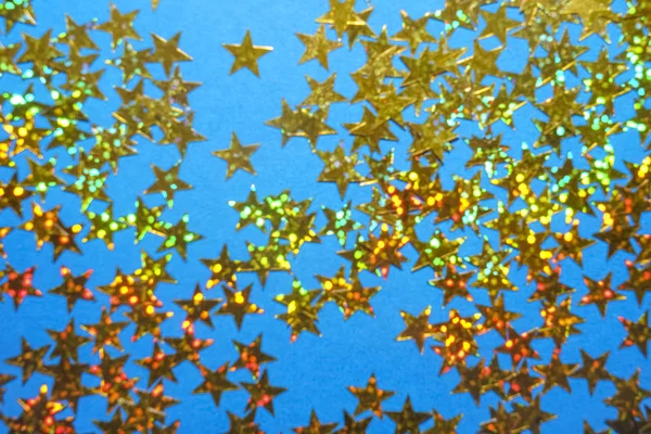 Golden yellow stars glitter lie isolated on blue  background. Festive holiday bright backdrop. happy new year and merry Christmas holidays.