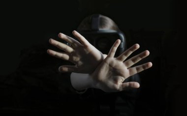 Ciddi, mutsuz, kendine güveni tam iki kolu çapraz tutan, işaret eden, siyah arka plandaki VR cihazına bakan genç bir kız.