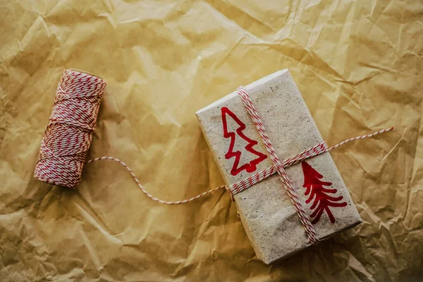 Christmas theme. Handmade Gift wrapping for Christmas and 2020 New Year. wrapping christmas gift in craft paper and thread,  on table. Wrapping stylish new year gifts concept