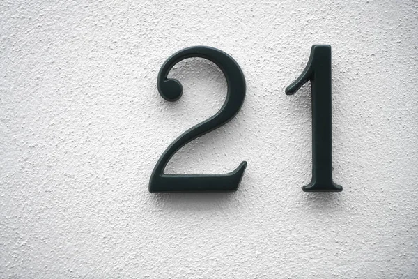 metal number 21 house number on white wall background.  twenty one digit.