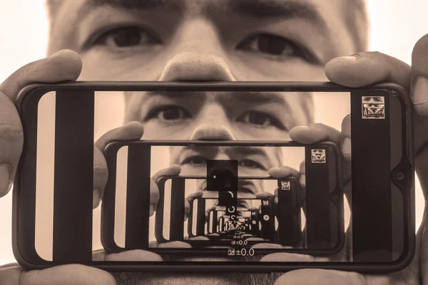 2つの鏡面の間に効果を乗算します 男性の顔を遠近感で再現 携帯電話の画面の画像です男の肖像 — ストック写真