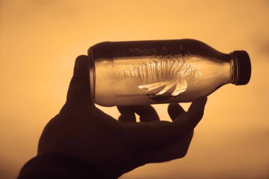 Adam arka planda gökyüzü etiketi olmadan cam şişeyi elinde tutuyor.. 