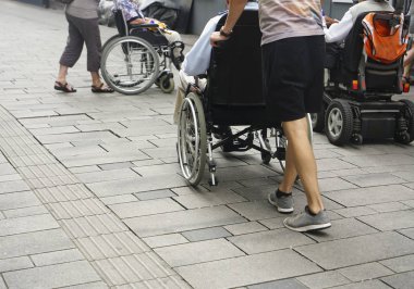 Staten Staten Street 'te tekerlekli sandalyeyi iten birinin ayaklarına yakından bakın. Tekerlekli sandalyenin arkasındaki çocuk ve büyükbabası.