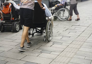 Staten Staten Street 'te tekerlekli sandalyeyi iten birinin ayaklarına yakından bakın. Tekerlekli sandalyenin arkasındaki çocuk ve büyükbabası.