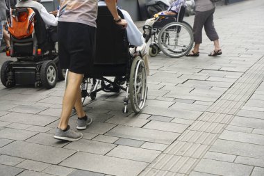 Staten Staten Street 'te tekerlekli sandalyeyi iten birinin ayaklarına yakından bakın. Tekerlekli sandalyenin arkasındaki çocuk ve büyükbabası.