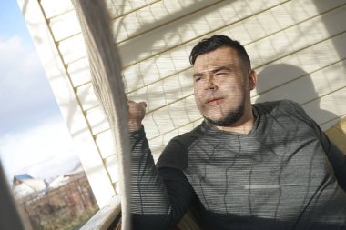 Yakışıklı adamın Venedik Panjur ile pencere yanında.