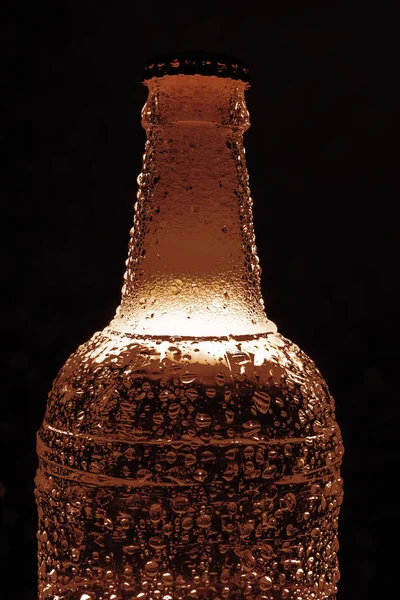 golden Beer with foam - dark beer in transparent  bottle. Isolated on black  background