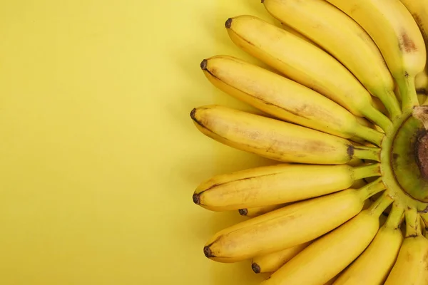 Butch of small bananas isolated on yellow paper background.  empty copy space for inscription.
