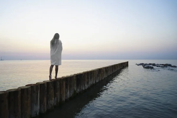 金发美女的晨游 在日落海滩上散步的白人金发姑娘 直达地平线 后视镜 后视镜 白湿巾披在肩上 — 图库照片