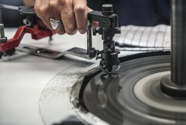 Amsterdam 'ın Dünya Skills sırasında dönen demir turuna bağlı bir mücevherin son yüzleri üzerinde çalışan bir cilalayıcı.. 