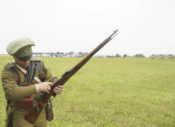 Man with rifle dressed in russian soldier uniform of first World War I. charges the cartridge in the shutter