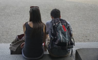 Genç mutlu çift taş merdivenlerde oturuyor ve kağıt haritaya bakıyor. Berlin, Almanya. 