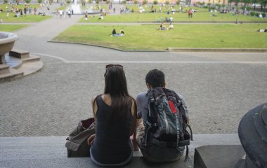 Genç mutlu çift taş merdivenlerde oturuyor ve kağıt haritaya bakıyor. Berlin, Almanya. 