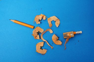 Kırık sarı kalem ve ahşap kalemtıraş mavi kağıt arka planda. 