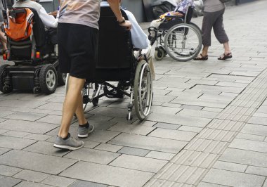 Staten Staten Street 'te tekerlekli sandalyeyi iten birinin ayaklarına yakından bakın. Tekerlekli sandalyenin arkasındaki çocuk ve büyükbabası.