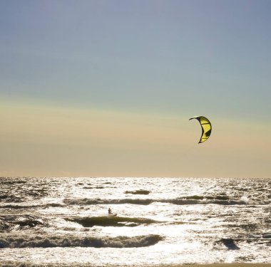 Rüzgâr Sörfçüsü Panorama 'sı, Surfing.Strong Rüzgârları bu Rüzgar Sörfçüsüne yardım ediyor. Suda eğlenen ve uçurtmayla sörf yapan bir adamın silüeti. Güçlü rüzgarlarla dalgaları tutuyor.. 
