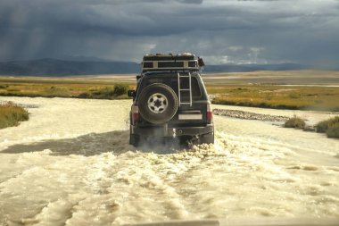 4 'e 4 siyah araba su sıçratan bir nehri geçiyor, off-road macerası için seyahat konsepti ve dağ manzarası için eğlence. 