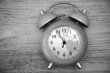 Ahşap masa arkaplanındaki klasik saat ya da çalar saat. kadrandaki küresel harita küresi