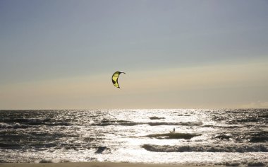 Rüzgâr Sörfçüsü Panorama 'sı, Surfing.Strong Rüzgârları bu Rüzgar Sörfçüsüne yardım ediyor. Suda eğlenen ve uçurtmayla sörf yapan bir adamın silüeti. Güçlü rüzgarlarla dalgaları tutuyor.. 