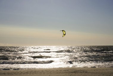 Rüzgâr Sörfçüsü Panorama 'sı, Surfing.Strong Rüzgârları bu Rüzgar Sörfçüsüne yardım ediyor. Suda eğlenen ve uçurtmayla sörf yapan bir adamın silüeti. Güçlü rüzgarlarla dalgaları tutuyor.. 