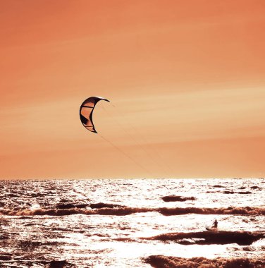 Rüzgâr Sörfçüsü Panorama 'sı, Surfing.Strong Rüzgârları bu Rüzgar Sörfçüsüne yardım ediyor. Suda eğlenen ve uçurtmayla sörf yapan bir adamın silüeti. Güçlü rüzgarlarla dalgaları tutuyor.. 
