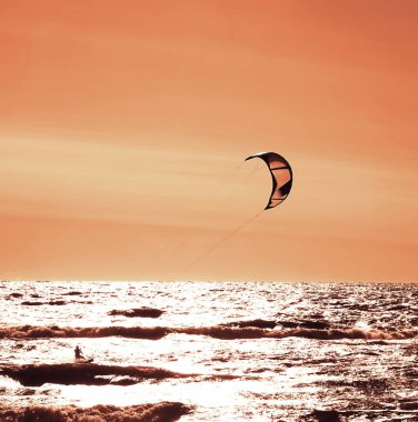 Rüzgâr Sörfçüsü Panorama 'sı, Surfing.Strong Rüzgârları bu Rüzgar Sörfçüsüne yardım ediyor. Suda eğlenen ve uçurtmayla sörf yapan bir adamın silüeti. Güçlü rüzgarlarla dalgaları tutuyor.. 