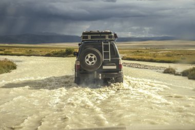 4 'e 4 siyah araba su sıçratan bir nehri geçiyor, off-road macerası için seyahat konsepti ve dağ manzarası için eğlence. 