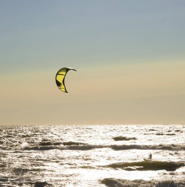 Rüzgâr Sörfçüsü Panorama 'sı, Surfing.Strong Rüzgârları bu Rüzgar Sörfçüsüne yardım ediyor. Suda eğlenen ve uçurtmayla sörf yapan bir adamın silüeti. Güçlü rüzgarlarla dalgaları tutuyor.. 