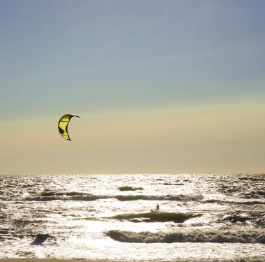 Rüzgâr Sörfçüsü Panorama 'sı, Surfing.Strong Rüzgârları bu Rüzgar Sörfçüsüne yardım ediyor. Suda eğlenen ve uçurtmayla sörf yapan bir adamın silüeti. Güçlü rüzgarlarla dalgaları tutuyor.. 